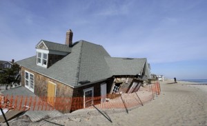 Un hombre toma fotografías a una casa en la playa en Bay Head, Nueva Jersey, el jueves 3 de enero de 2013, que fue severamente dañada hace dos meses por el paso de la supertormenta Sandy. El viernes 4 de enero, la Cámara de Representantes de EEUU aprobó un fondo de 9.700 millones de dólares para cubrir los reclamos de seguros por inundación para muchos propietarios de hogares y negocios afectados por Sandy. (Foto AP/Mel Evans)