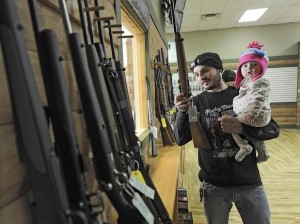 Tyler Hook manipula un rifle mientras carga a su hija Emma de 11 meses en la armería Highsmith Guns, en Greenfield, California, el 2 de enero de 2013. Estados Unidos sufre muchas más muertes violentas comparado con otra nación desarrollada debido en parte a la extendida posesión de armas de fuego, reveló un estudio. Foto: Daily Reporter/Tom Russo / AP