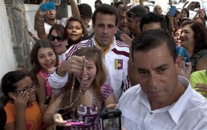 El candidato presidencial opositor Henrique Capriles es rodeado por partidarios mientras sale de su casa para votar en los comicios presidenciales en Caracas, Venezuela, el domingo 14 de abril de 2013. (Foto AP/Ramón Espinosa)
