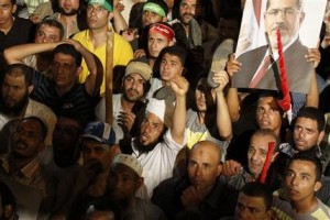 Partidarios del derrocado presidente islamista de Egipto, Mohammed Morsi, escuchan el mensaje por televisión de las fuerzas armadas anunciando la instalación de un gobierno civil temporal y convocar a nuevas elecciones, el miércoles 3 de julio de 2013. (Foto AP/Mohammed Maymooni, El Shorouk Newspaper)