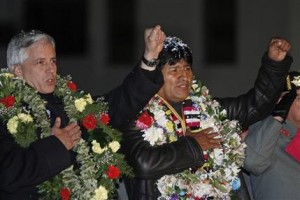 El presidente de Bolivia Evo Morales, a la derecha, y su vicepresidente Alvaro Garcia Linera cantan el himno nacional al arribar a El Alto, Bolivia, el miércoles 3 de julio de 2013 tras permanecer más de trece horas varado en Austria adonde desvió su vuelo tras salir de Rusia después de que Francia, España, Portugal e Italia le negaran cruzar por su espacio aéreo ante la sospecha de que pudiera estar ocultando al ex agente estadounidense Edward Snowden en su avión. (AP foto/Juan Karita).