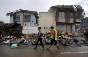 Dos personas pasan junto a cadáveres de las víctimas del tifón Haiyan, el sábado 16 de noviembre del 2013, en la ciudad de Taclobán, en el centro de las Filipinas. (Foto AP/Wong Maye-E)