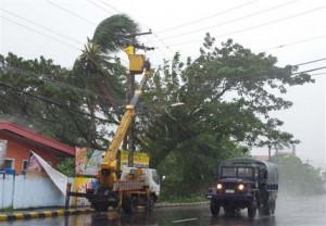 Un vehículo militar recorre una zona afectada mientras trabajadores eléctricos tratan de restaurar el servicio tras el paso del poderoso tifón Haiyan en la ciudad de Legazpi, provincia de Albay, unos 520 kilómetros (325 millas) al sur de Manila, Filipinas, el viernes 8 de noviembre de 2013. (AP Foto/Nelson Salting)