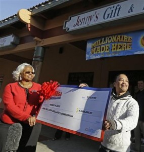 El dueño de la tienda de regalos Jenny's, Thuy Nguyen, a la derecha, recibe su cheque por un millón de dólares de la represntante de ventas de la lotería de California, Mona Sanders, el miércoles 18 de diciembre de 2013. La tienda de Nguyen vendió uno de los boletos ganadores del sorteo Mega Millions del martes en la noche que alcanzó la cifra casi histórica de 646 millones de dólares.(AP Foto/Ben Margot)