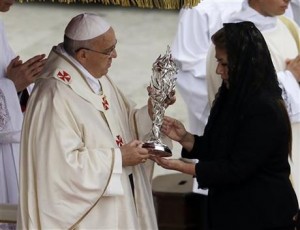 Floribeth Mora, una mujer de Costa Rica afectada por un aneurisma cerebral inoperable que presuntamente desapareción después de que ella le rezó a Juan Pablo II toma uno de los objetos que guardan las reliquias del papa durante su ceremonia de canonización en domingo 27 de abril de 2014. (Foto de AP/Alessandra Tarantino)