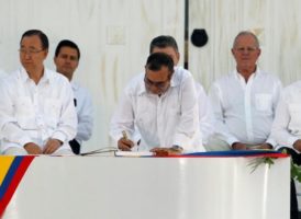 El líder rebelde marxistas Rodrigo Londono (C), mejor conocido como Timochenko, firma el acuerdo que pone fin a un conflicto armado con medio siglo de duración y que mantuvo a Colombia herida, ante la mirada de los 2.500 invitados que asistieron a la ceremonia, vestidos de blanco, donde hubo 15 mandatarios, como el cubano Raúl Castro. También estuvieron el secretario de Estado de Estados Unidos, John Kerry, y víctimas del conflicto. REUTERS/John Vizcaino